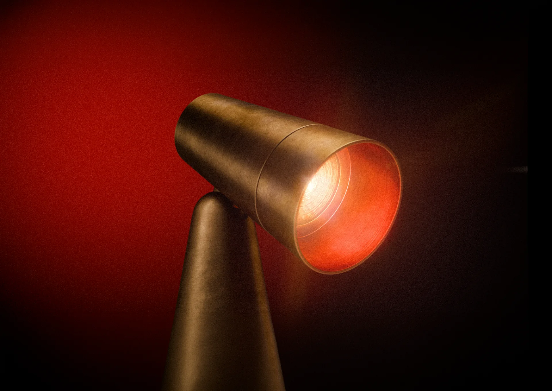 The brass head of Table Lamp 001 glowing red against a red wall